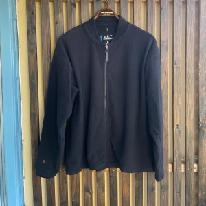 Svart fleece från Matterhorn - Svart fleecekofta från Matterhorn med dragkedja framtill och hög krage. Koftan har lång ärm och enkel, stilren design utan synliga fickor. Perfekt för lager-på-lager och chill dagar.