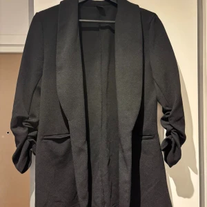 Kofta/jacka - Stilren och enkel svart kavaj/kofta ,bekvämt tyg. Perfekt både till vardag. Har lätt rynkade ärmar och två fickor framtill. Sitter snyggt och ger en elegant look.