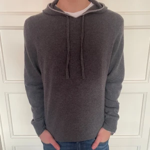 stickad grå hoodie merinoull & kashmir - mörkgrå stickad hoodie i merinoull & kashmir. riktigt snygg och i toppskick. Från Paul Costelloe. Storlek L och grabben på bilden är 183 cm lång. tveka inte att slänga iväg ett meddelande för fler bilder eller vid frågor! 