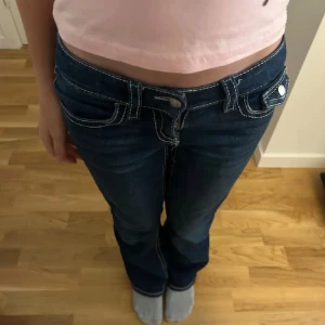 Blå bootcut jeans från Gina Tricot - Mörkblå jeans från Gina Tricot i storlek 152 med bootcut-modell och kontrastsömmar. Klassisk femficksdesign med ficklock bak och låg midja. Perfekta för dig som gillar en retro vibe och snygg passform.