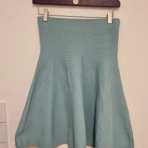 Ljusblå stickad kjol från mint&berry - Supersöt ljusblå/grön stickad kjol från mint&berry i en skön, mjuk kvalitet. Kjolen har en utsvängd form och hög midja som ger en snygg siluett. Perfekt att styla med en enkel topp eller stickad tröja.