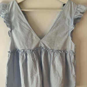 Ljusblå volangklänning från Zara - Supersöt ljusblå topp från Zara, den har inga större tecken på användning! Säljer pga att den är för liten!