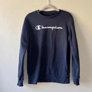 Mörkblå Champion tröja - Snygg mörkblå långärmad tröja från Champion med vit logga framtill. XL men barnstorlek bör passa 13-14 åringar enligt lapp