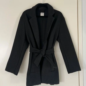 Only höstkappa - Säljer en mörk grå medellång höstkappa med knyte i midjan. Använd, nopprig på vissa ställen men har försökt ta bort det mesta. Samlar åt sig hår. Liten o storleken, passar även en S! Varm o perfekt till hösten🥰