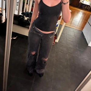 Svarta baggy jeans med slitningar - Säljer ett par svarta baggy jeans med slitna knän och vida ben. Jeansen har klassisk femficksdesign, hög midja och är tillverkade i denim. 
