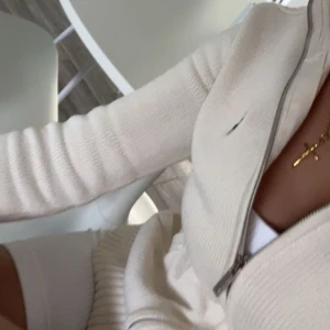 Vit stickad kofta från Ralph Lauren - Säljer en stilren vit stickad kofta från Ralph Lauren med dragkedja framtill och diskret marinblå logga på bröstet. Koftan har lång ärm och är perfekt för lager-på-lager. Passar dig som gillar klassisk och fräsch stil.