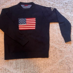 Mörkblå Gant stickad tröja med USA-flagga - Säljer en mörkblå stickad tröja från Gant i 100% bomull. Tröjan har ett broderat amerikanskt flaggmotiv på bröstet och ribbade muddar vid ärmslut och nederkant. Klassisk rund halsringning och långärmad modell. Perfekt för dig som gillar preppy stil!   ÄR ÖPPEN FÖR PRISJUSTERING, SKRIV FÖR MINSTA FUNDERINGAR, kolla vidare i min profil för liknande kläder. 