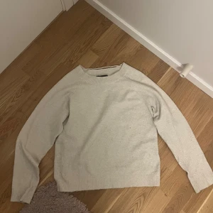 Beige stickad tröja från Vero Moda - En enkel och stilren beige stickad tröja från Vero Moda. Tröjan har rund halsringning, långa ärmar och ribbade muddar vid ärmslut och nederkant. Perfekt för lager-på-lager och passar till allt.