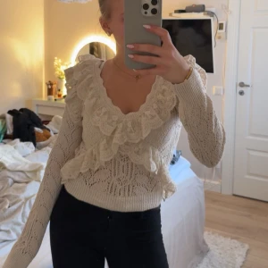 Beige spetsblus med volang från Zara - Superfin beige blus från Zara med v-ringning, volanger och spetsdetaljer. Stickad känsla med genombrutet mönster och långa ärmar. Perfekt för dig som gillar romantisk och feminin stil. Säljs i storlek S. Inga defekter och knappt använd 