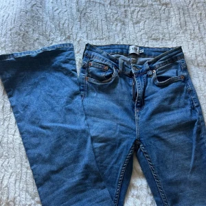 Blå flare jeans från 157 - Snygga blå jeans från 157 med klassisk femficksdesign och flare-ben. Jeansen har normal passform och är tillverkade i mjukt denimtyg. Perfekta för dig som gillar retrovibbar och vill ha ett par jeans som sticker ut lite extra.