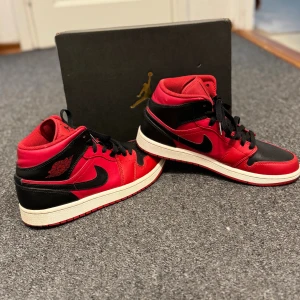 Nike Air Jordan 1 Mid Svart/Röd - Säljer ett par Nike Air Jordan 1 Mid i klassisk svart och röd färg med  röda sulor. Nästan helt oanvända kommer med skokartongen, vill bara bli av med de därav det låga priset!! STL 41