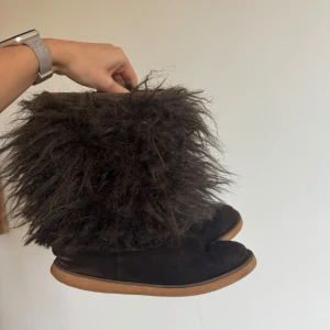 Bruna fluffiga boots med päls - Unika bruna boots med superfluffig päls på skaftet och mjuk, vit fodring inuti. Yttermaterialet är mocka. Perfekta för dig som vill sticka ut och hålla dig varm under kalla dagar.