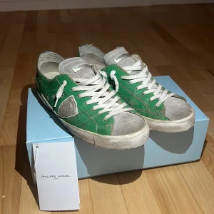 Gröna Philippe Model sneakers i skinn - Säljer ett par gröna Philippe Model sneakers med vit sula och grå detaljer. Skorna har snörning, rund tå och är tillverkade i skinn med en cool krackelerad finish. Märkeslogga på sidan och under sulan. Perfekta för dig som gillar streetstyle, och vill sticka ut!            Pris går att diskutera.