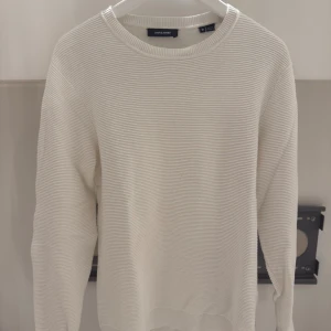 Vit ribbad tröja från Jack & Jones - Säljer en stilren vit tröja från Jack & Jones i storlek M. Tröjan har ett ribbat mönster och rund halsringning. Materialet är mjukt och känns skönt mot huden, perfekt för dig som gillar enkel och clean stil. Långa ärmar och klassisk passform.