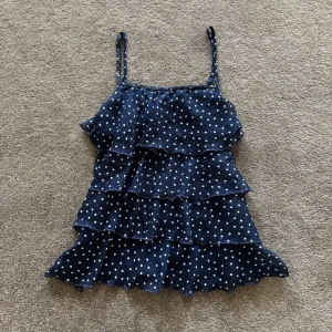 Mörkblå prickig volang-linnetopp - Supersöt mörkblå linne-topp med vita prickar och flera volanglager. Storlek XS/S