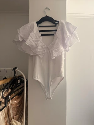 Vit volangbody - Supersnygg vit body från Zara med stora volangärmar och djup v-ringning. 