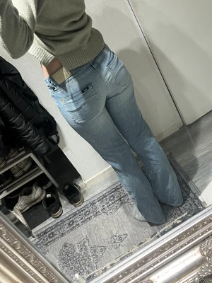 Ljusblå bootcut jeans från Lee - Säljer ett par ljusblå jeans från Lee med klassisk bootcut passform. Jeansen har låg midja, raka ben och snygga bakfickor med Lee-logga. Storlek W26 L31. 36/37cm midjemått 