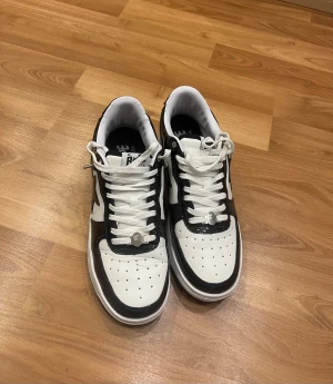 Svarta och vita BAPE STA sneakers - Säljer ett par BAPE STA sneakers i svart och vitt med blank finish. Skorna har den ikoniska stjärnan på sidan.  STORLEK 47 NY SKICK 