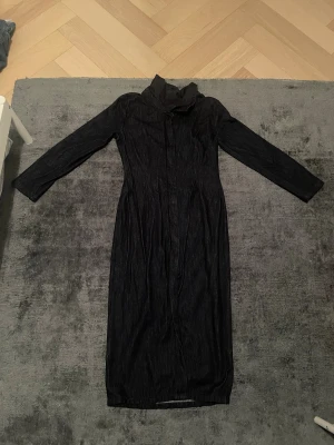 Svart långärmad jeansklänning från Zara - Säljer en svart lång jeansklänning från Zara med lång ärm och hög krage. Klänningen har dragkedja framtill och är figurnära i modellen. Materialet är klassiskt denim och insidan är ljusare. Perfekt för dig som gillar stilrena och tidlösa plagg.