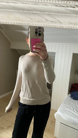 Beige långärmad tröja från 157 - Snygg beige långärmad tröja från 157, perfekt för dig som gillar enkla och stilrena plagg. Tröjan har rund hals och är tillverkad i mjuk viskosblandning med ribbade muddar vid ärmslut och nederkant, den är tunnt stickad. Passar dig som vill ha en clean och chill look.