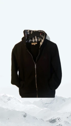 Svart Burberry hoodie med dragkedja - Svart hoodie från Burberry i bomull med klassiskt rutigt foder i huvan. Tröjan har dragkedja framtill, fickor och snörning i huvan. Perfekt för dig som vill ha nått bekvämt, väldigt bra kvalitet och är i toppskick 