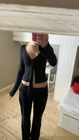 Svart omlottopp från Gina Tricot XS - Svart långärmad omlottopp från Gina Tricot i storlek XS. Toppen har djup v-ringning och knyt framtill, vilket ger en snygg croppad look. Tillverkad i mjukt och stretchigt material som sitter skönt på kroppen.