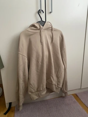 Beige hoodie från 157, XS - Säljer en beige hoodie från 157 i storlek XS. Tröjan har huva med snörning, ribbade muddar och är fodrad med mjuk fleece på insidan. Perfekt för dig som gillar en loose och chill stil. Passar dig som vill ha en enkel och clean look.