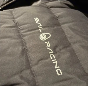 Svart dunväst från Sail Racing - Svart dunväst från Sail Racing med quiltad design och dragkedja framtill. Västen har en stilren look med logga på bröstet och ryggen. Perfekt för lager-på-lager och håller dig varm under kyliga dagar.