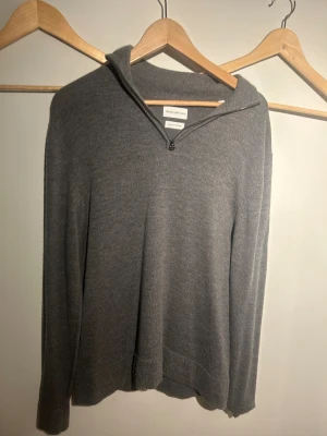 Grå merinoulltröja med half zip - Snygg grå långärmad tröja från These Glory Days i mjuk superior merinoull. Tröjan har en stilren half zip-dragkedja vid halsen och en klassisk passform. Perfekt för dig som gillar minimalistisk och clean stil. Tveka inte en sekund på att höra av dig kring eventuella frågor runt pris och annat!