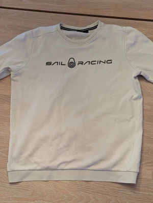 Vit Sail Racing sweatshirt - Vit sweatshirt från Sail Racing. Använd men inga effekter. Några små små prickar på magen men inget som syns. Inget pris som är hugget i sten så det är bara att höra av dig vid minsta fråga om pris eller funderingar!