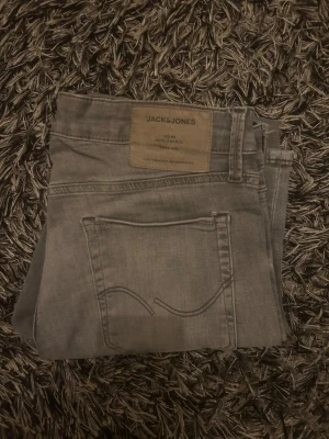 Grå skinny jeans från Jack & Jones 30/30 - Snygga grå jeans från Jack & Jones i modellen Jeans Intelligence. De har en skinny passform med klassisk femficksdesign och diskreta sömmar på bakfickan. Perfekt för dig som gillar en smal siluett och stilren look.