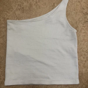 Vit ribbad oneshoulder topp - Säljer en vit ribbad topp med oneshoulder-design. Från Gina tricot i storlek xs 