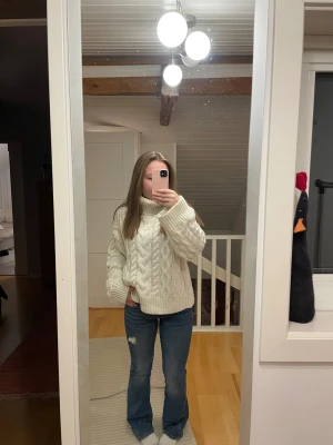 Vit stickad polotröja med flätmönster - Säljer en chunky vit stickad polotröja med breda ärmar och snyggt flätmönster. Tröjan har hög krage och är riktigt mysig och oversized, perfekt för kyliga dagar. Passar dig som gillar en avslappnad och trendig stil.