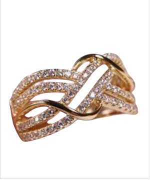 Glittrig guldring med stenar - Snygg guldfärgad ring med glittrande stenar i ett flätat, vågigt mönster. Ringen har flera rader av små gnistrande stenar som ger en lyxig och trendig känsla. Perfekt för dig som vill sticka ut med ett statement-smycke.