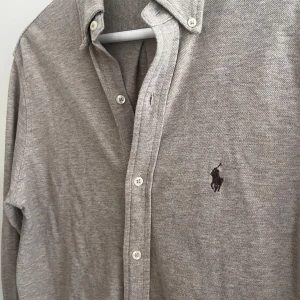 Ralph Lauren skjorta - Säljer nu en riktigt snygg featherweight mesh skjorta, passar till allt med färgen beige👔. Skjortan är grön Ralph Lauren och är väldigt skön och bra kvalitet🐎. Den är trendig och passar nu till vår/vinter då den är lite tjockare🌌. Använd några gånger men inget synligt slitage. Tröjan är storlek xs men sitter som S. Priset är inte hugget i sten🪨 så hör av er vid funderingar. Skick:7/10✅                                       Ny pris:1789kr🙈                             Mitt pris:449kr👌🏼