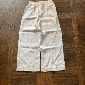 Vita linnebyxor med snörning från Zara - Snygga vita linnebyxor från Zara med avslappnad passform och elastisk midja med snörning. Byxorna har raka ben och är tillverkade i ett luftigt linnematerial, perfekta för varma dagar. Stilrena och enkla att matcha till olika outfits.