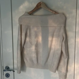 Offshoulder stickad tröja från H&M - Säljer en krämvit stickad offshoulder-tröja från H&M i storlek 164. Tröjan har bred ribbad kant upptill och vid ärmslut, samt lång ärm. 