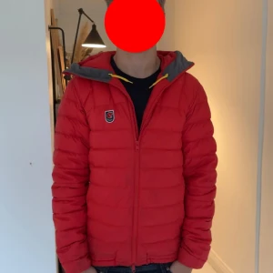 Röd pufferjacka från Fjällräven - Säljer en röd pufferjacka från Fjällräven med huva och dragkedja. Köptes ny för 6000kr, storlek S, Jackan har en quiltad look, gul snörning vid huvan och klassisk Fjällräven-logga på bröstet. Perfekt för kyliga dagar, säljer då den inte passar mig, priset är inte spikat så kom med bud😌