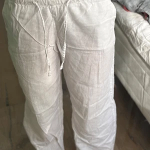 Vita linnebyxor från Gina Tricot - Säljer ett par vita linnebyxor från Gina Tricot med avslappnad passform och dragsko i midjan. Byxorna har elastisk midja och är tillverkade i svalt linnematerial, perfekta för varma dagar. Stilrena och enkla att matcha med det mesta.