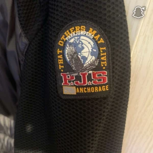 Svart pufferjacka från Parajumpers M - Säljer en svart pufferjacka från Parajumpers i storlek M. Äkta, Jackan har snygga detaljer som orange dragkedja, broderad patch på ärmen och quiltad yta. Perfekt för dig som vill ha en varm och stilren jacka med coola detaljer och sportig känsla. Säljs billigt och kan sänkas vid snabb affär. 