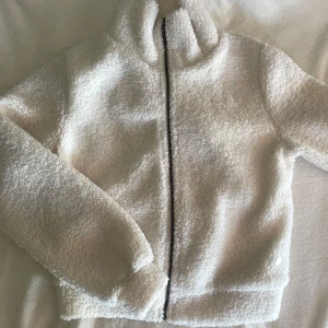 Vit teddyjacka - Vit teddyjacka med krage och hel dragkedja framtill och fickor. Jackan har en lagom oversized känsla. Passar även S, pris kan diskuteras vid snabb affär