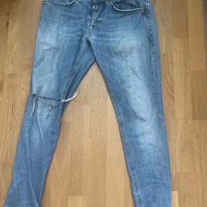 Dondup jeans med slitningar - Säljer ett par blå jeans från Dondup i storlek 33. Jeansen har klassisk femficksdesign, slitningar och trasig detalj vid knät för en cool, avslappnad look. Kontraststickningar och Dondup logga bak. Vid frågor eller funderingar är det bara att skriva!