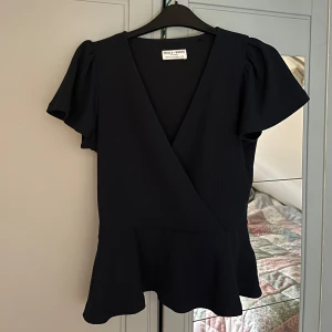 Mörkblå omlottopp💗💗 - Snygg mörkblå omlottopp med korta ärmar och v-ringning. Perfekt för både vardag och fest. Den har en figursmickrande passform och är gjord i ett bekvämt material. Aldrig använd!