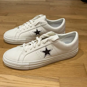 Vita Converse One Star (helt nya) - Helt oanvända vita Converse One Star sneakers med svart stjärna på sidan. Denna färg är slutsålda i många om inte alla storlekar. Råkade beställa fel storlek, därför säljer jag dem nu. Köptes in för 1450kr ifrån USA.