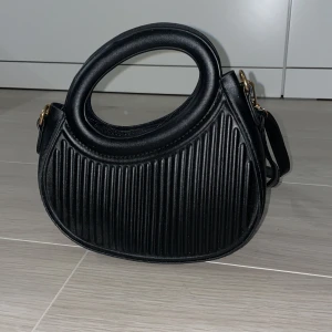 Svart axelväska med rundat handtag - Svart axelremväska med avtagbart band, liten i storlek