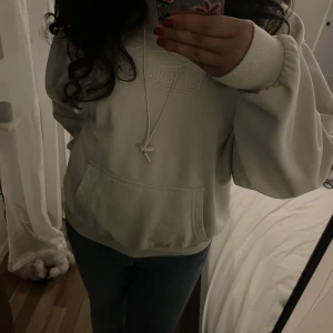 Vit hoodie från Kani i XS - Säljer en stilren vit hoodie från Kani i storlek XS. Hoodien har huva med snörning, magficka och broderad logga framtill. Perfekt för dig som gillar en clean och enkel look. Mjuk insida och ribbade muddar vid ärmslut och nederkant.