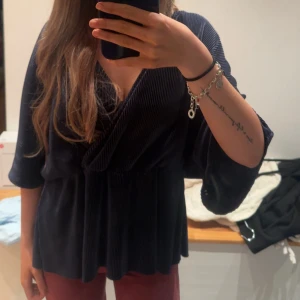 Mörkblå omlottkofta i manchester - Säljer en mörkblå omlottkofta i mjuk manchester med trekvartsärm och markerad midja. Koftan har en snygg omlottfront och ett lätt glansigt tyg som ger en lyxig känsla. Perfekt för dig som gillar en chill men ändå stilren look. Säljer då den är för stor