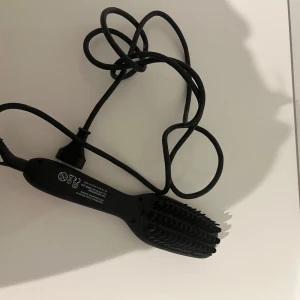 Elektrisk hårborste från Alessandra Ambrósio - Säljer en elektrisk hårborste med svart borsthuvud och guld/svart handtag. Borsten har knappar för temperaturinställning och en lång sladd med EU-kontakt. Perfekt för att styla och platta håret snabbt och enkelt.