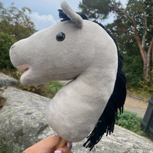 Käpphäst grå - Det här är min käpphäst den är använd några gånger men har legat i mitt garage nått år därför väljer jag att sälja den. Den är grå och mjuk pinnen är en träpinne.