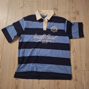 Blå randig Pikétröja - Helt ny, aldrig använt. Den kostade runt 200kr men nu säljer jag den för 100kr. Skulle ha på mig den till skolavslutningen men jag gjorde inte det.